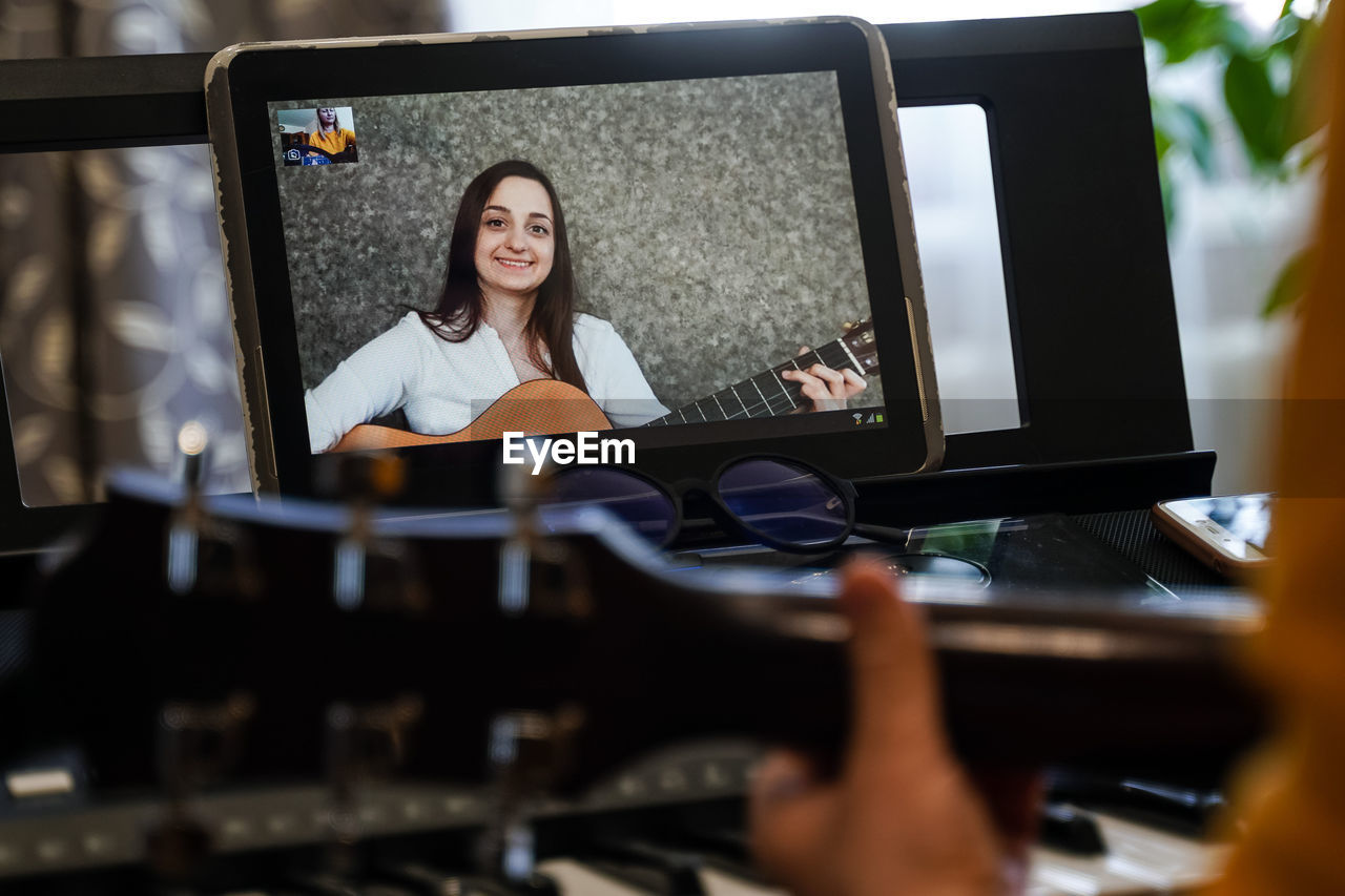 Cropped hand of woman playing piano while video conferencing over digital tablet at home