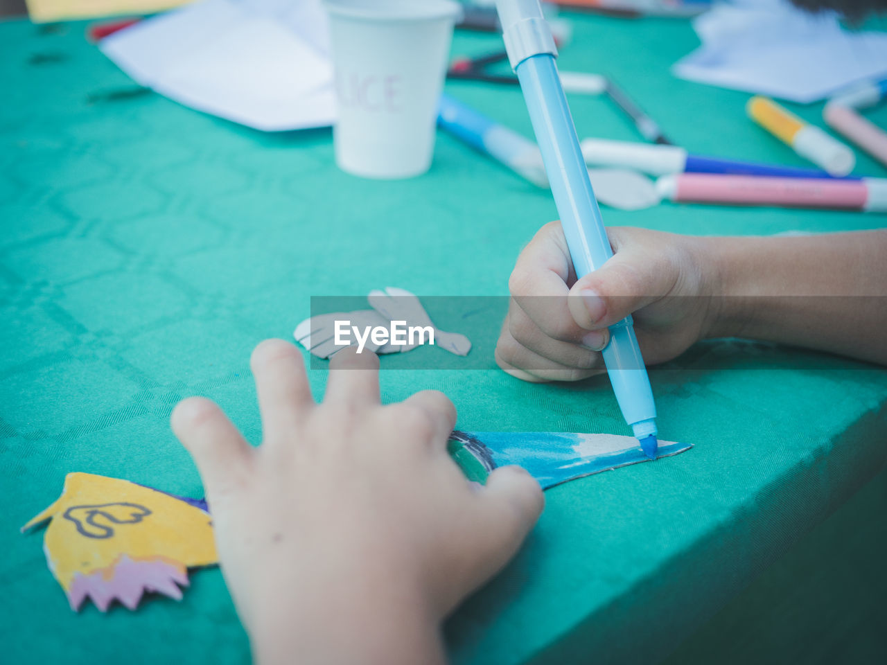 Cropped hand of person coloring over table