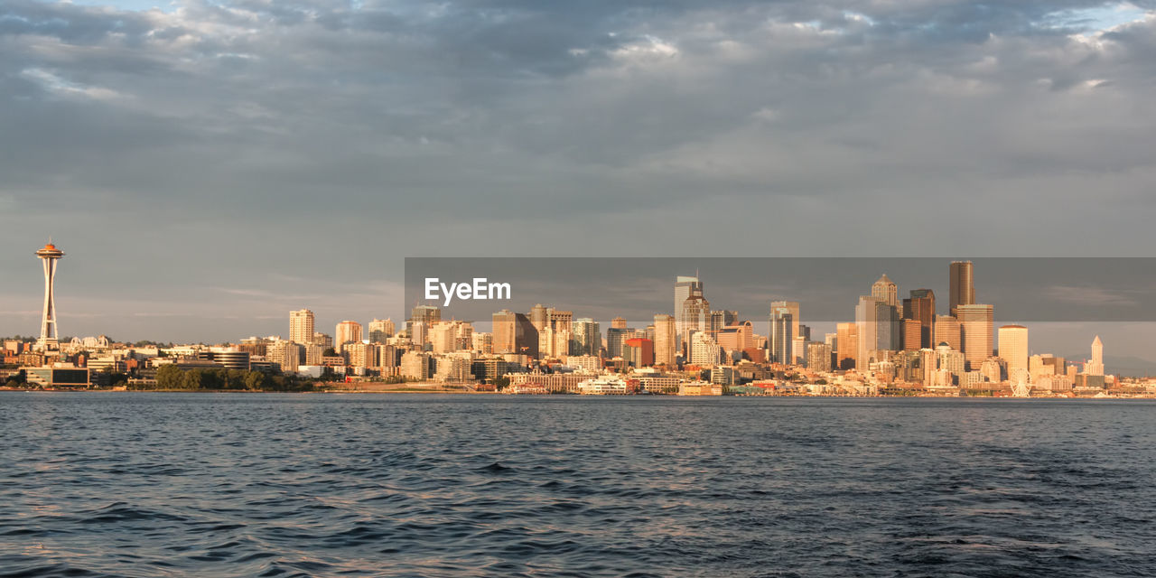 City skyline by sea against sky