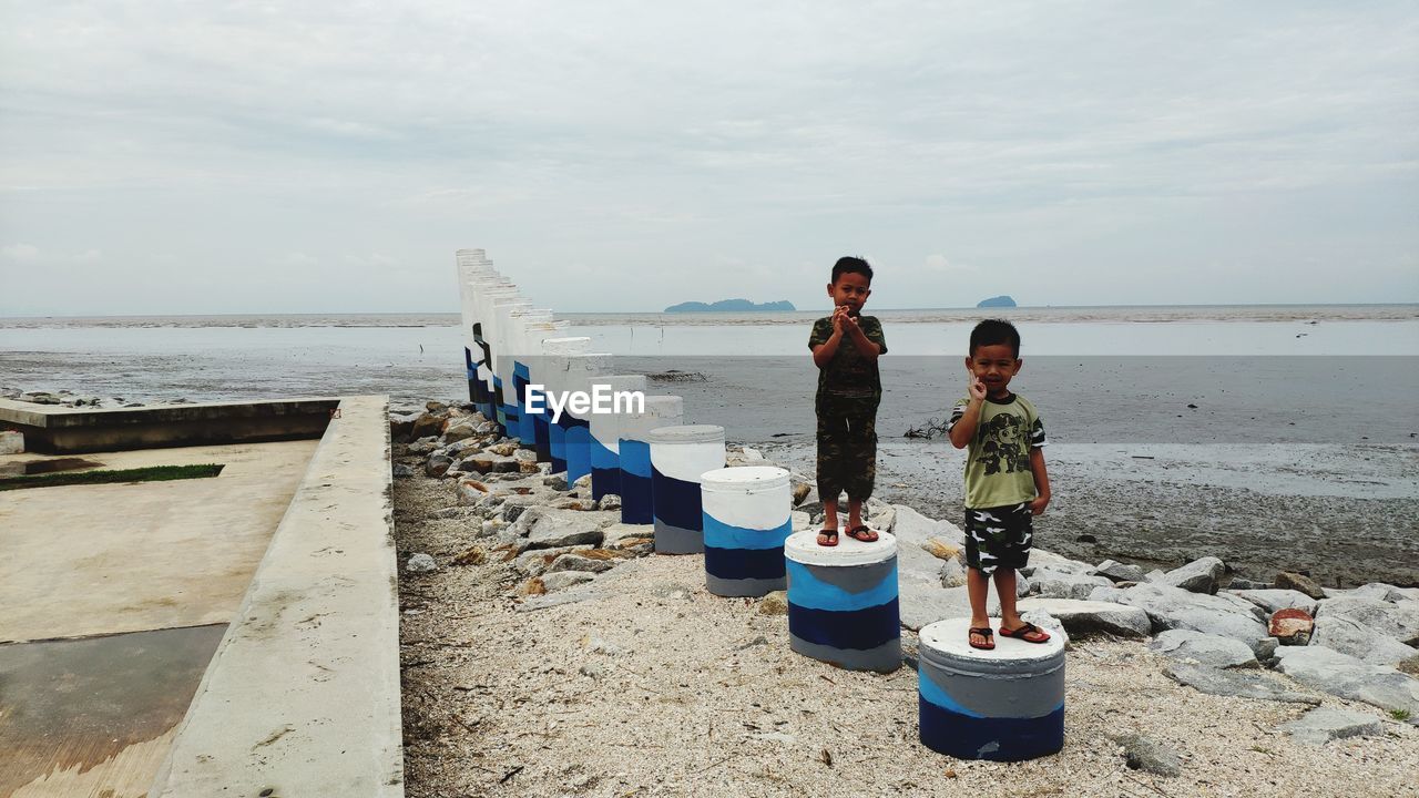 CHILDREN ON BEACH AGAINST SKY