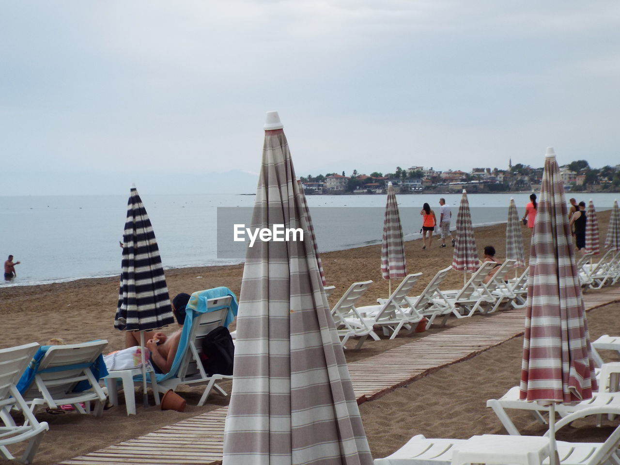 Lounge chairs and umbrellas at beach against sky