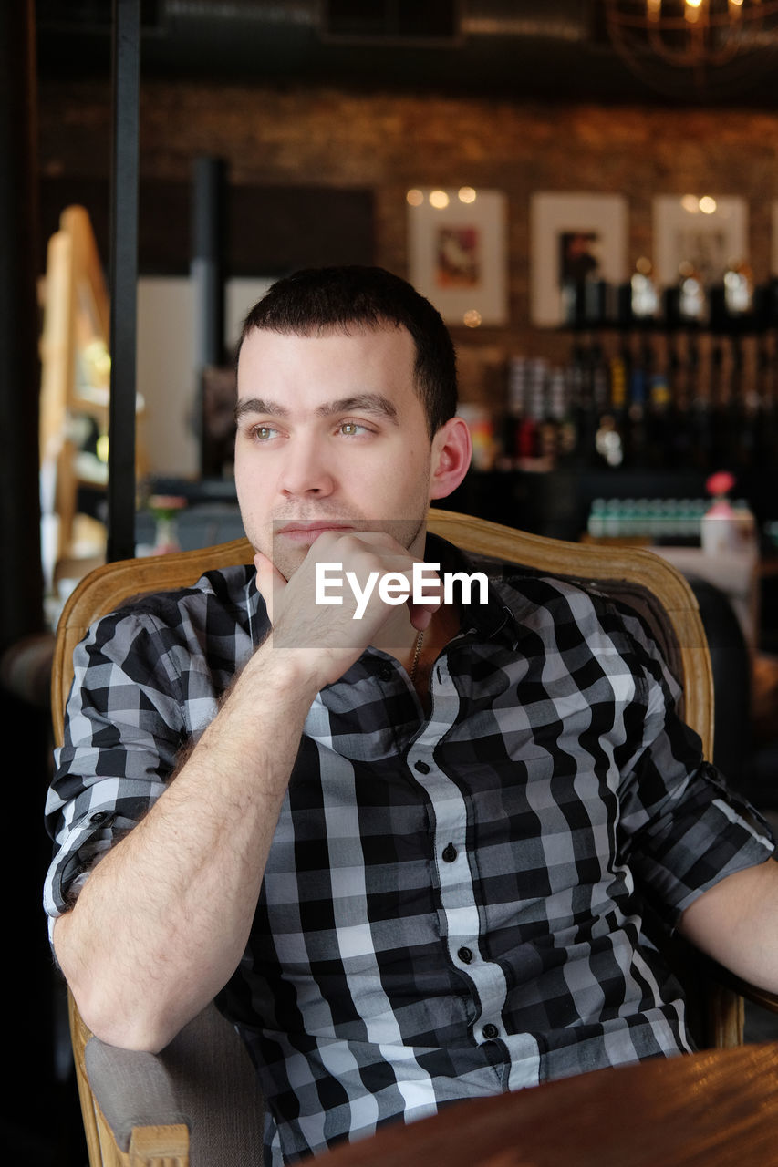 Man looking away while sitting at cafe