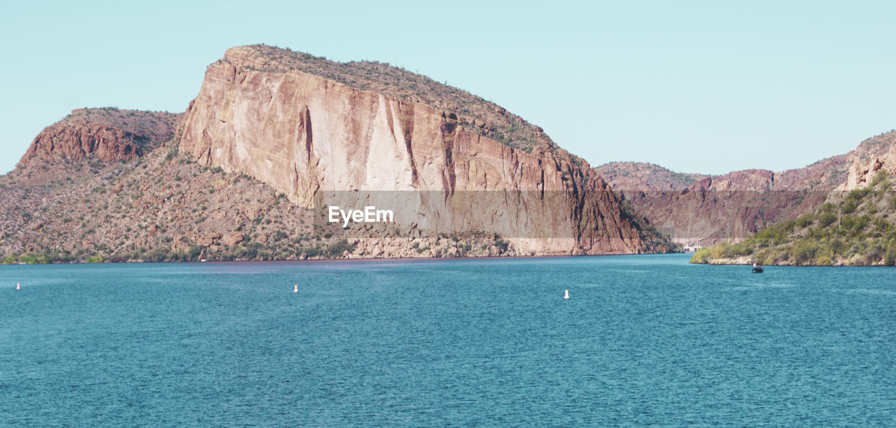 SCENIC VIEW OF SEA AND MOUNTAINS AGAINST CLEAR SKY