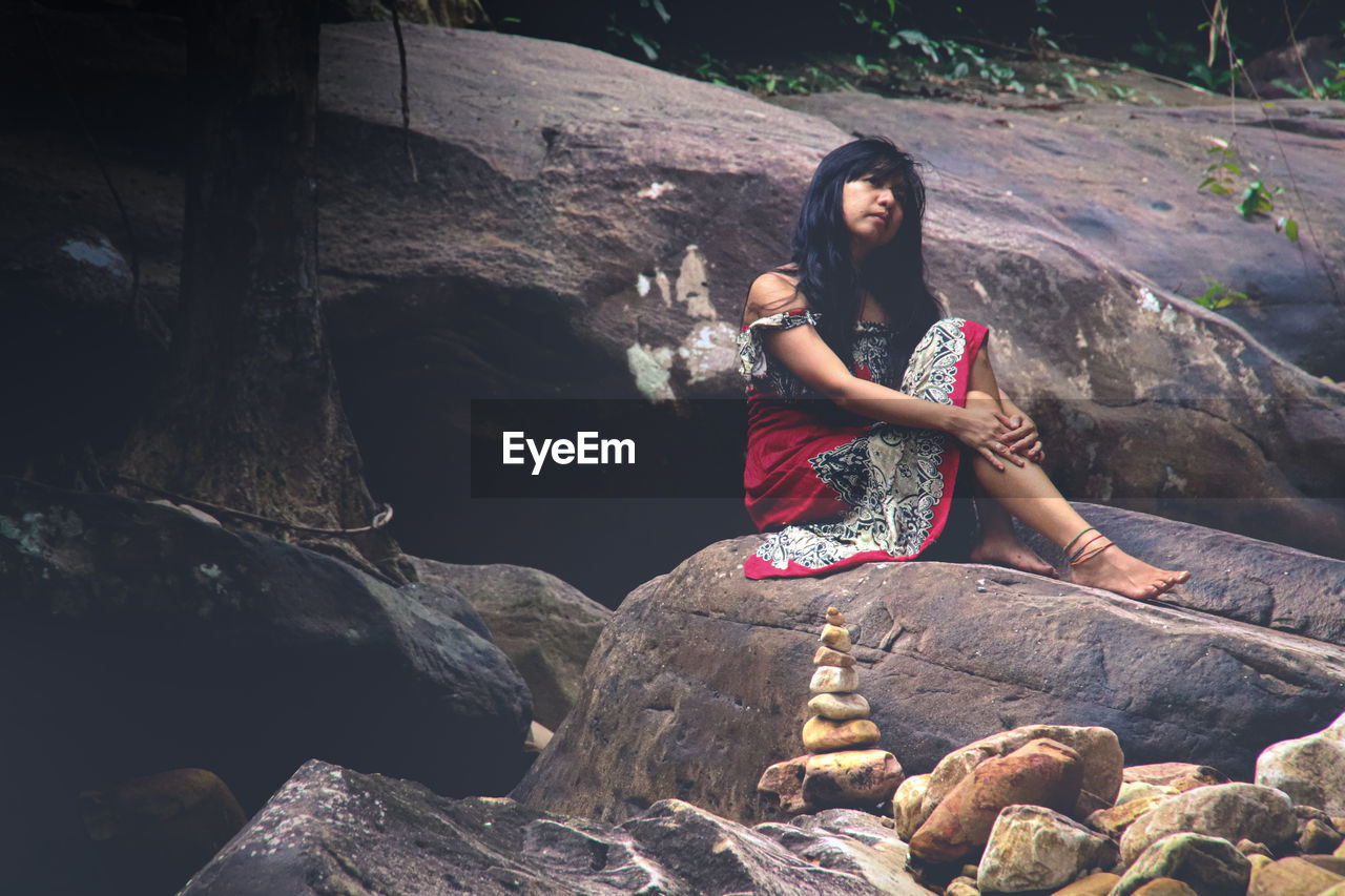 Thoughtful woman sitting on rock