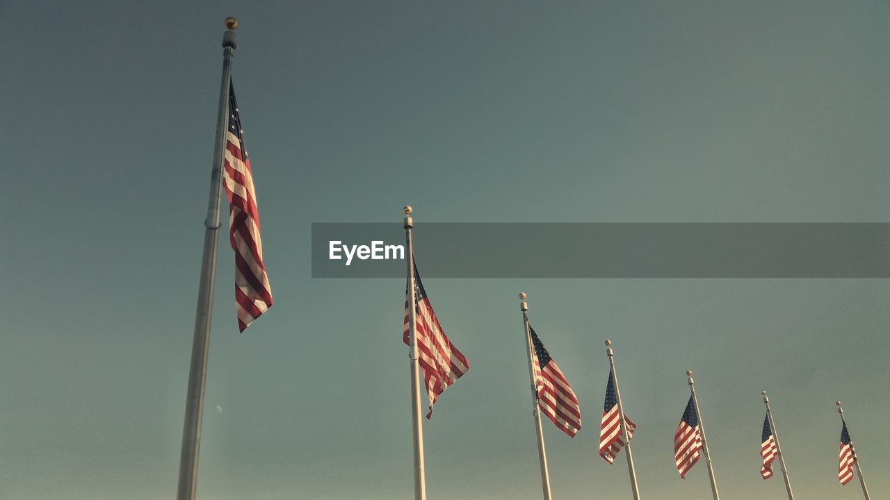 Low angle view of flags against clear sky