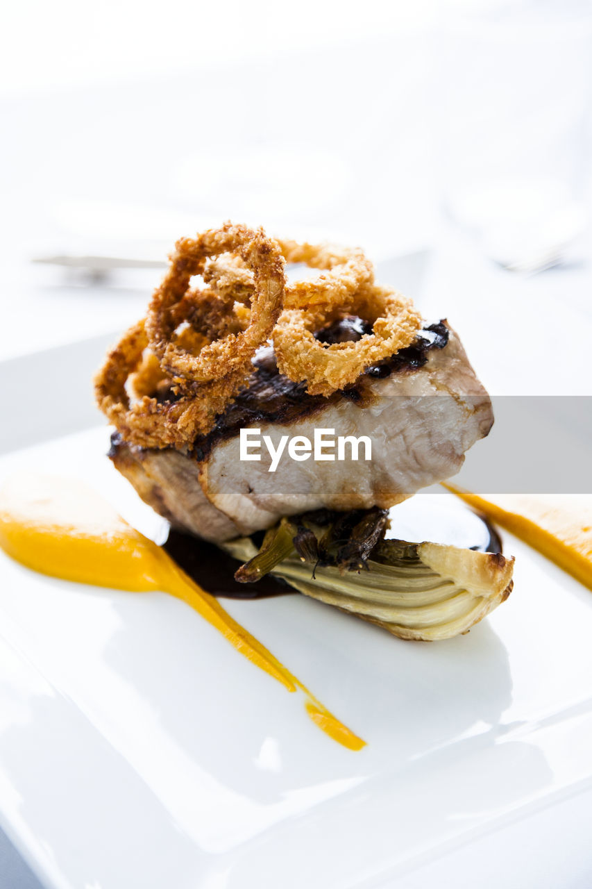 Grilled meat with onion rings on plate