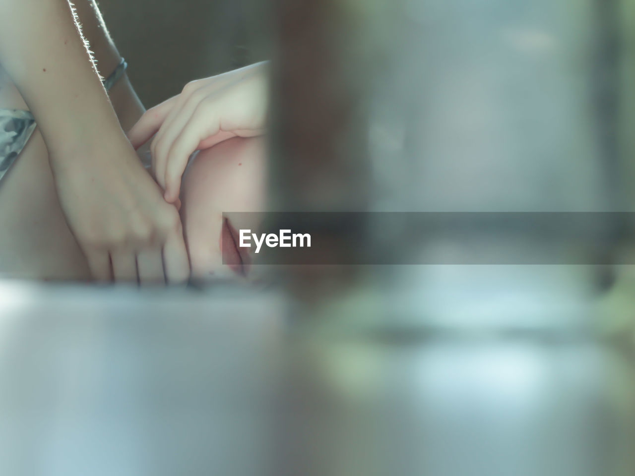 Midsection of young woman relaxing on bed seen through window