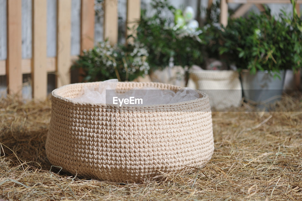 CLOSE-UP OF WICKER BASKET ON TABLE AGAINST PLANTS