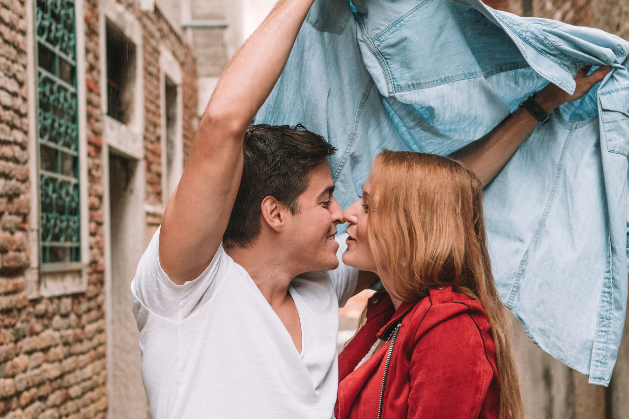 PORTRAIT OF A SMILING YOUNG COUPLE KISSING