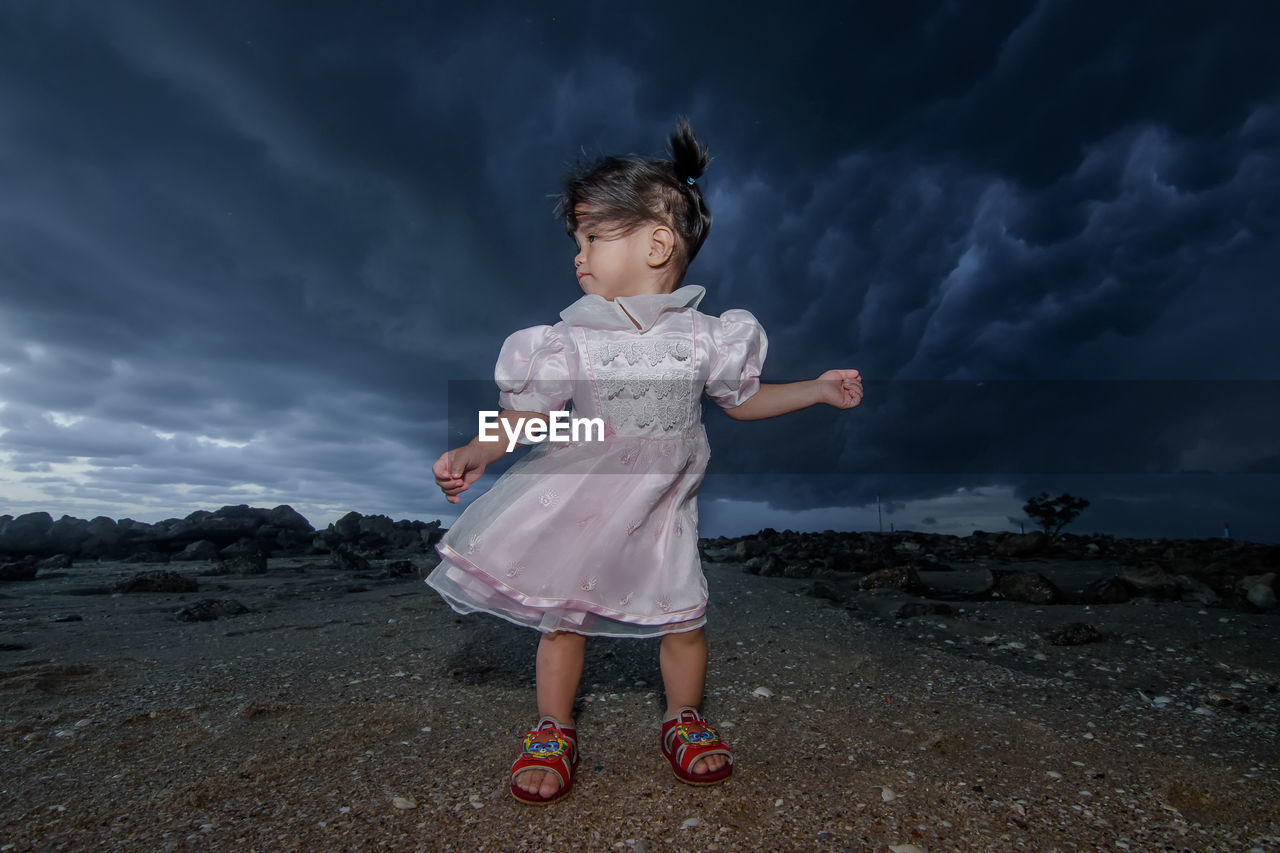 Girl standing on rock against sky