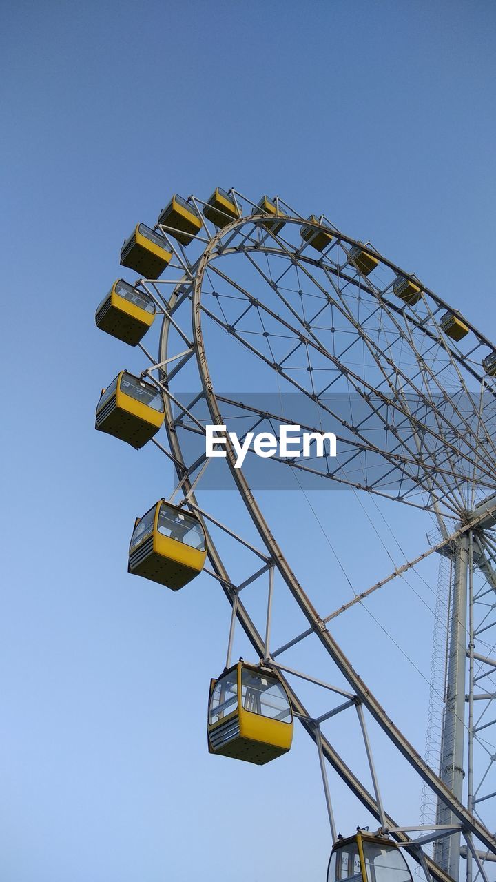 Low angle view of ferris wheel against clear blue sky