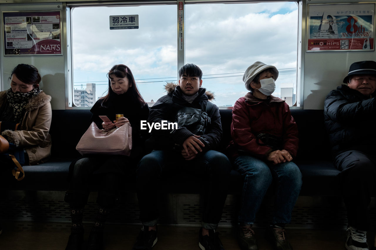 REAR VIEW OF PEOPLE SITTING ON SEAT IN TRAIN