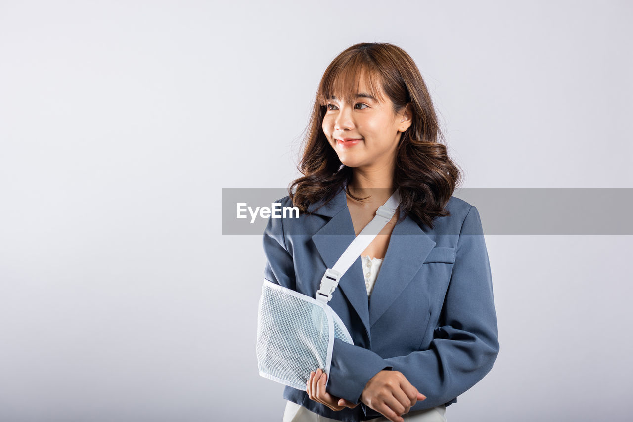 portrait of smiling young woman standing against white background