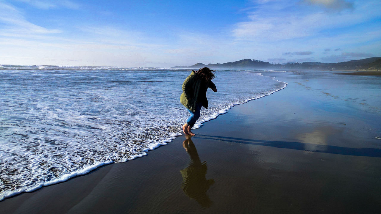 Woman walking by surf on shore at beach