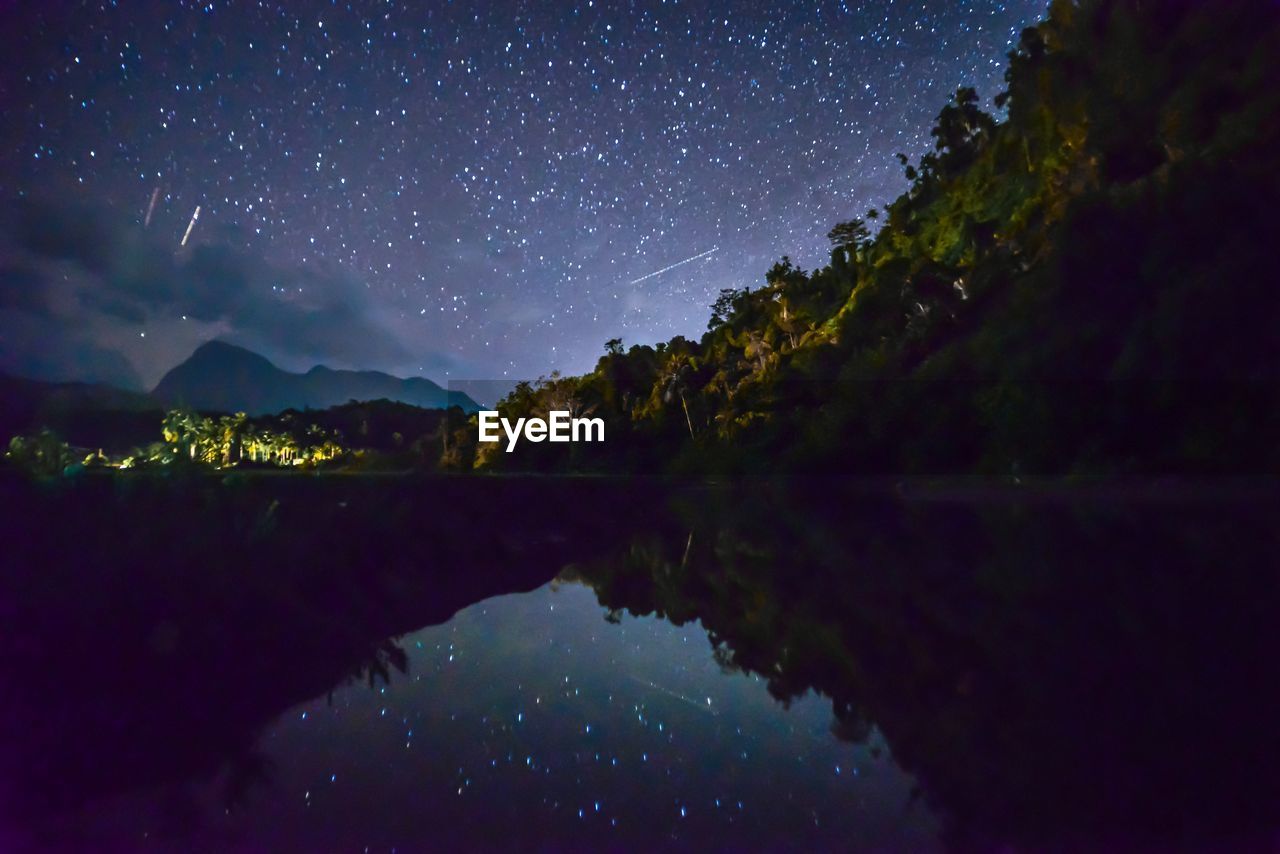 Scenic view of lake and mountains against sky at night