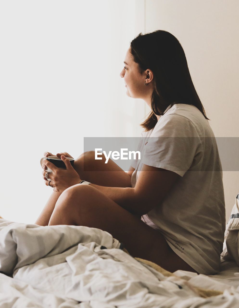 Young woman sitting on bed at home