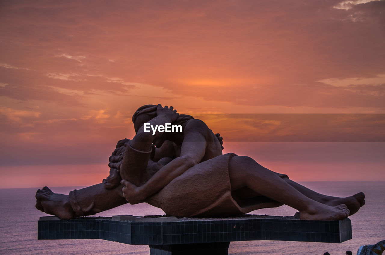 Statue against sea during sunset