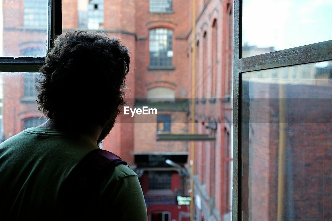 Rear view of man looking through window