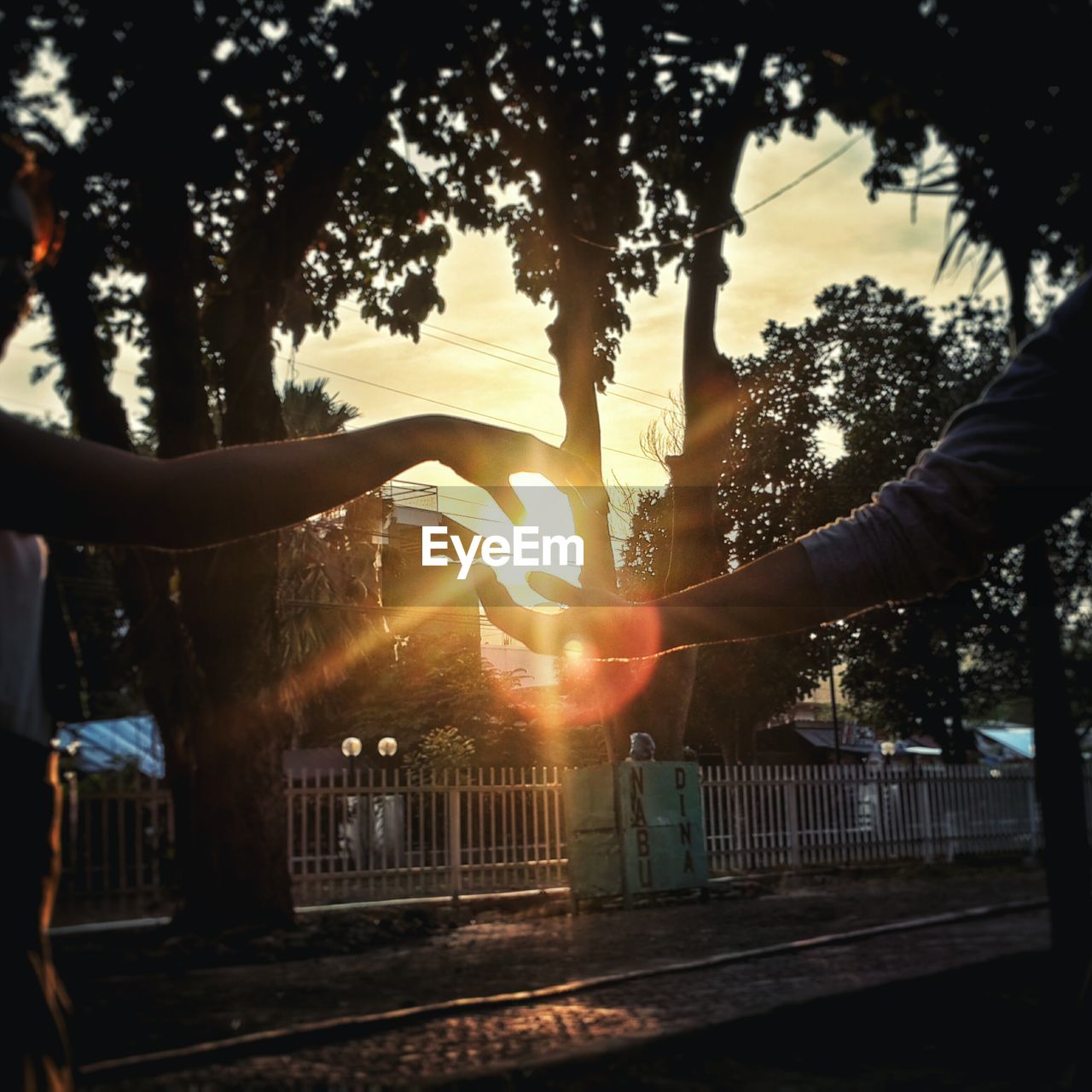 Optical illusion of couple holding sun at sunset