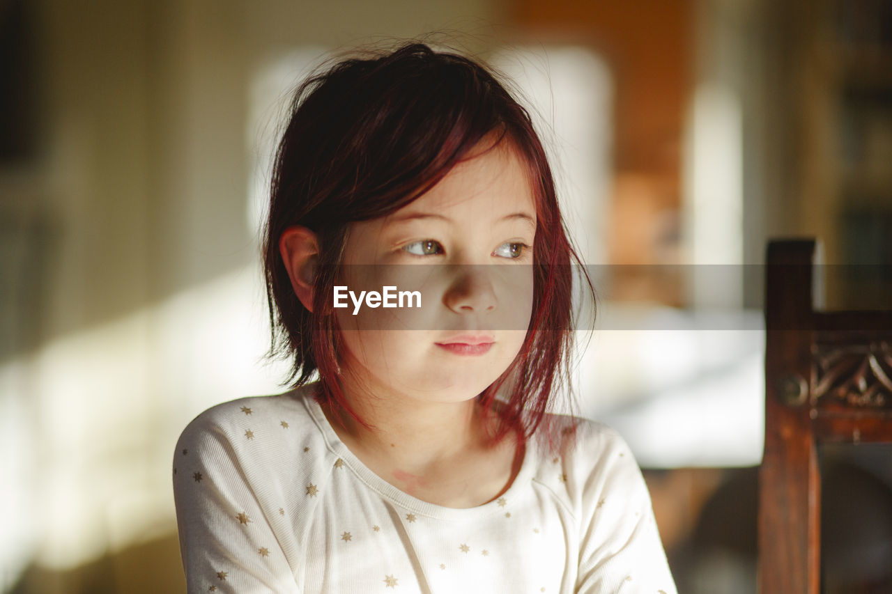 Portrait of small child with dyed red hair sitting in beautiful light