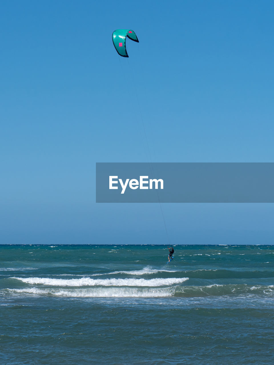 Kitesurfing during a windy day with a very rough sea.