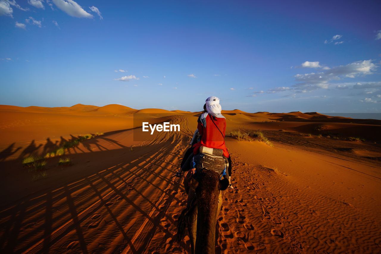 WOMAN WITH UMBRELLA WALKING ON DESERT