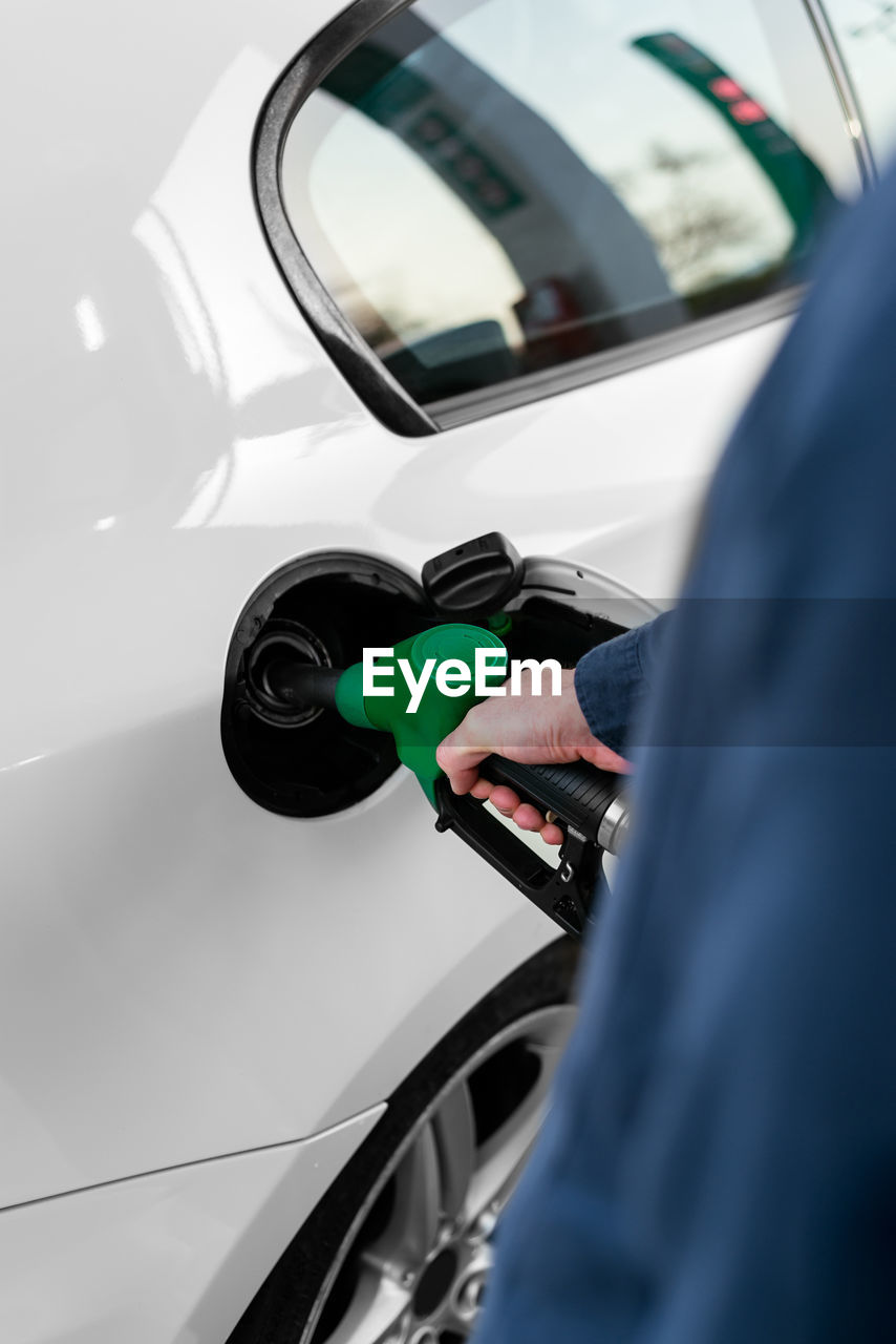 Cropped unrecognizable man refilling vehicle tank at petrol station during energy crisis