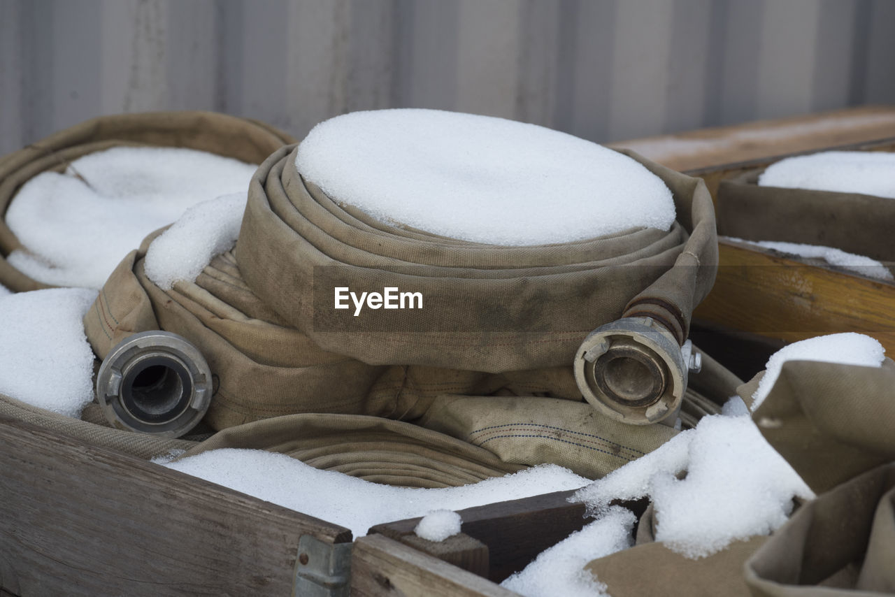 Coiled fire hoses laying in wooden boxes covered with snow