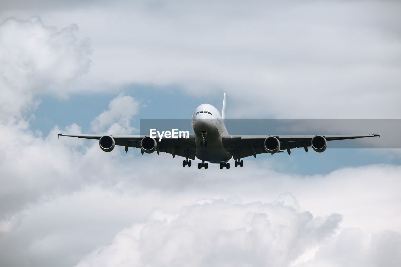 Huge airplane flying through clouds. plane approaching during landing at airport on sunny day.