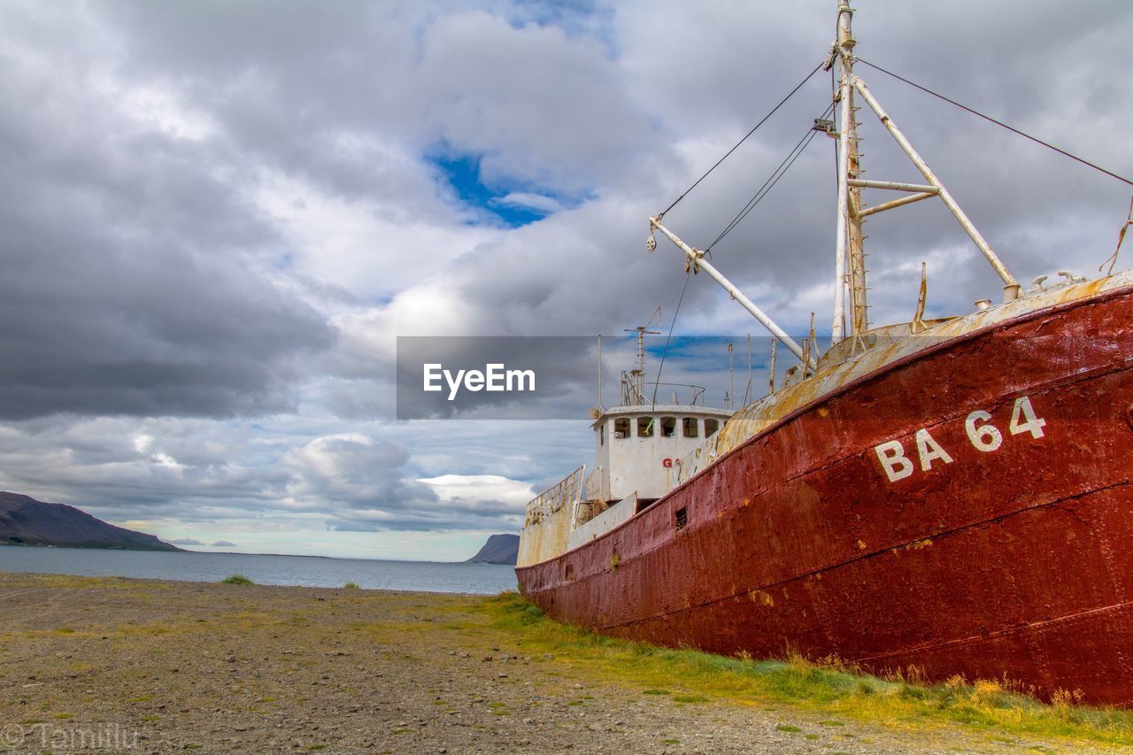 Sailboat moored on beach against sky