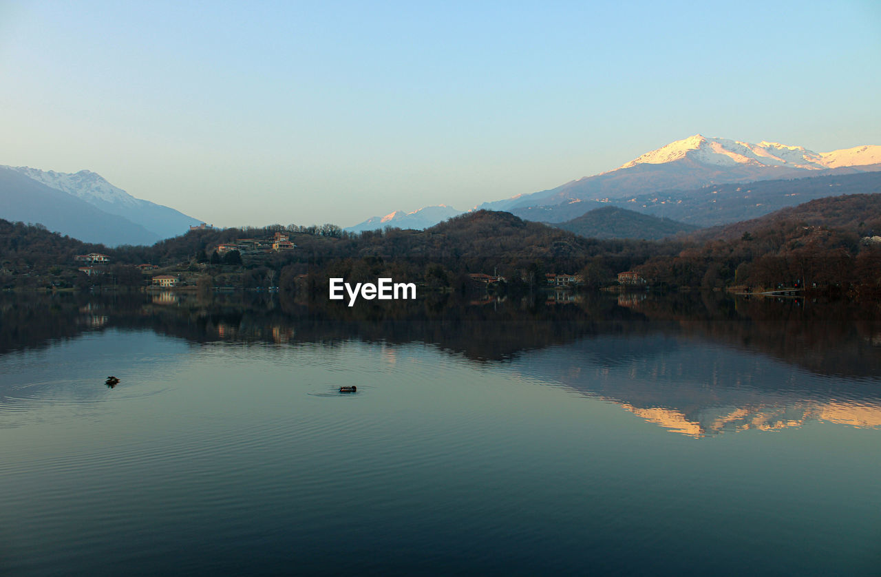 Scenic view of lake by mountains against clear sky