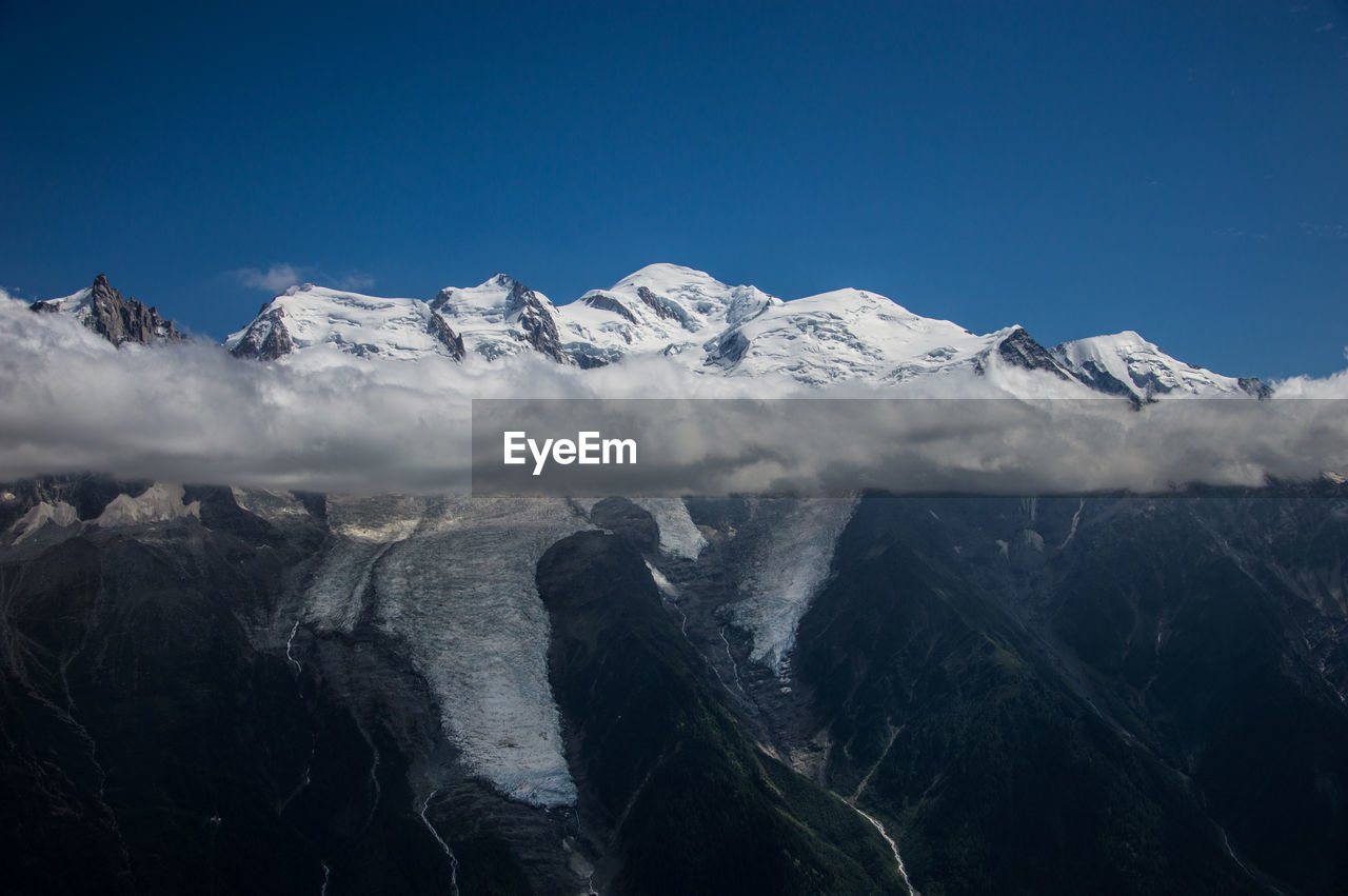 Scenic view of snowcapped mountains against clear blue sky