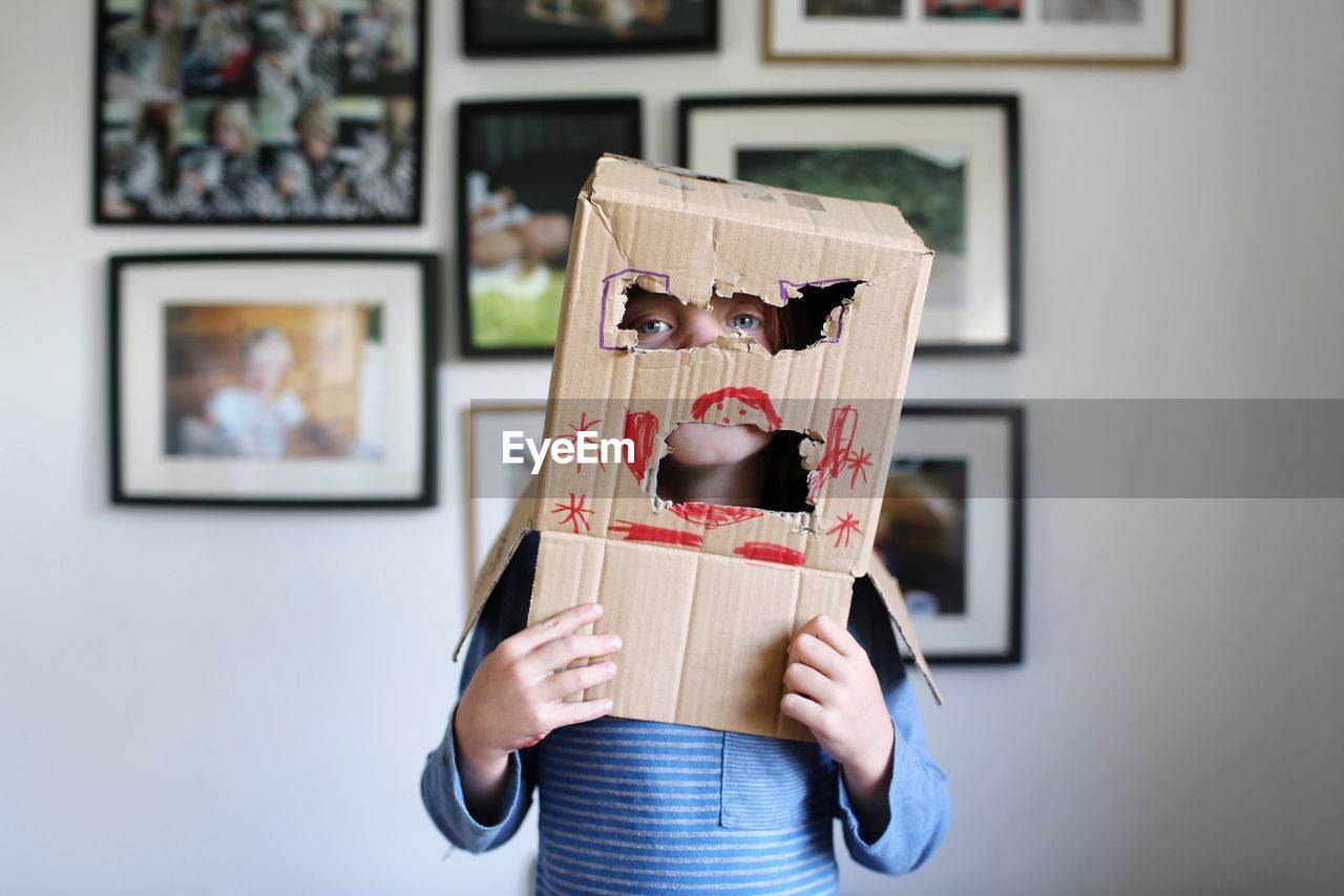Portrait of playful girl with cardboard box on head at home