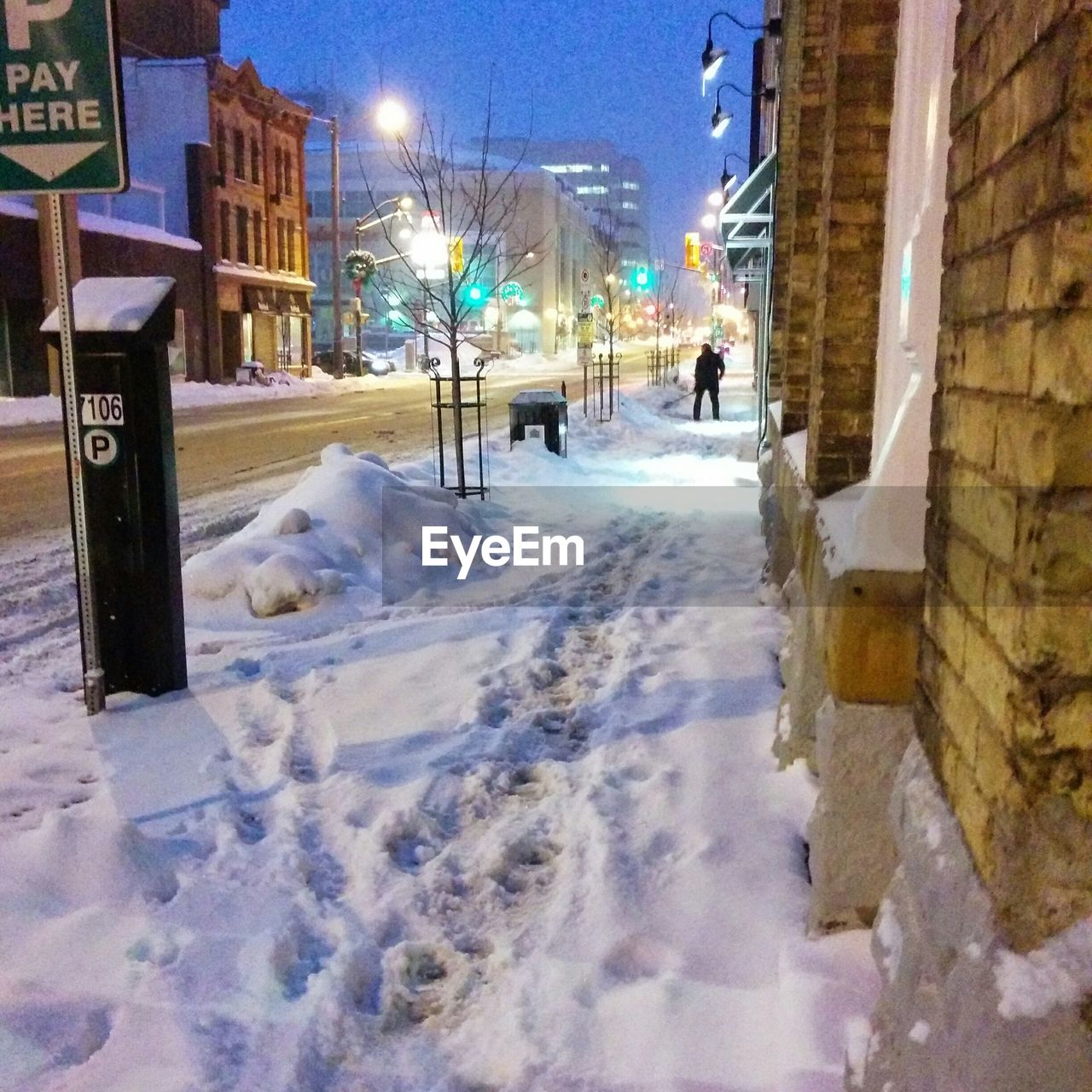 Snowcapped sidewalk in city at dusk