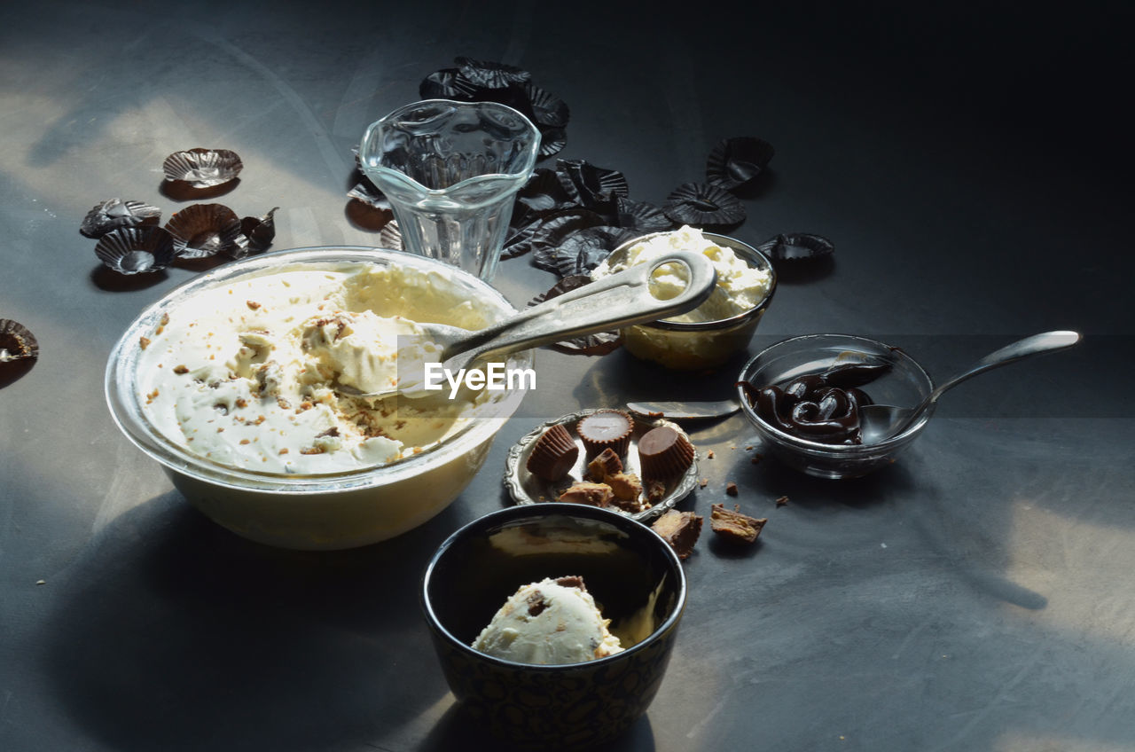 Ice cream in bowls with peanut butter cupcakes and chocolates on table