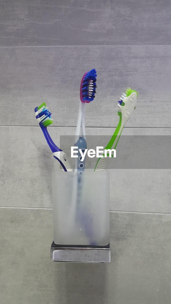 Close-up of toothbrushes in holder on wall