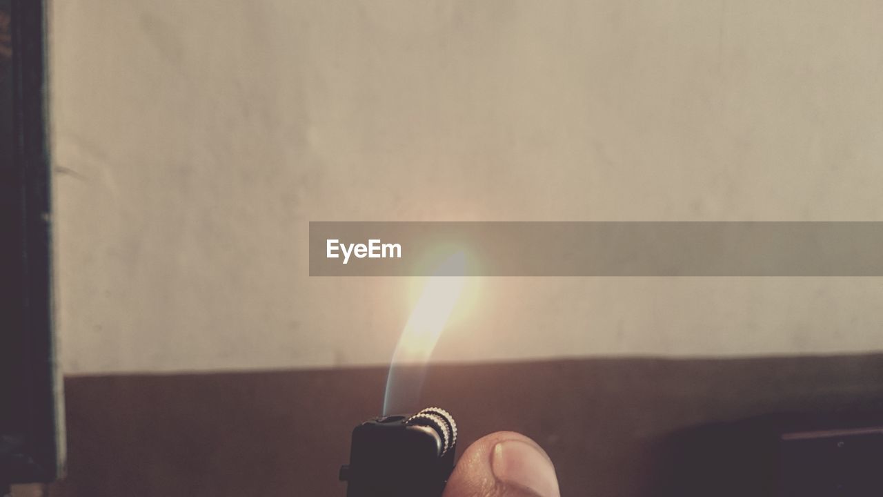 Cropped hand holding illuminated cigarette lighter