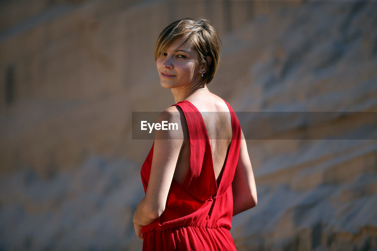 Portrait of young woman standing against rock formations