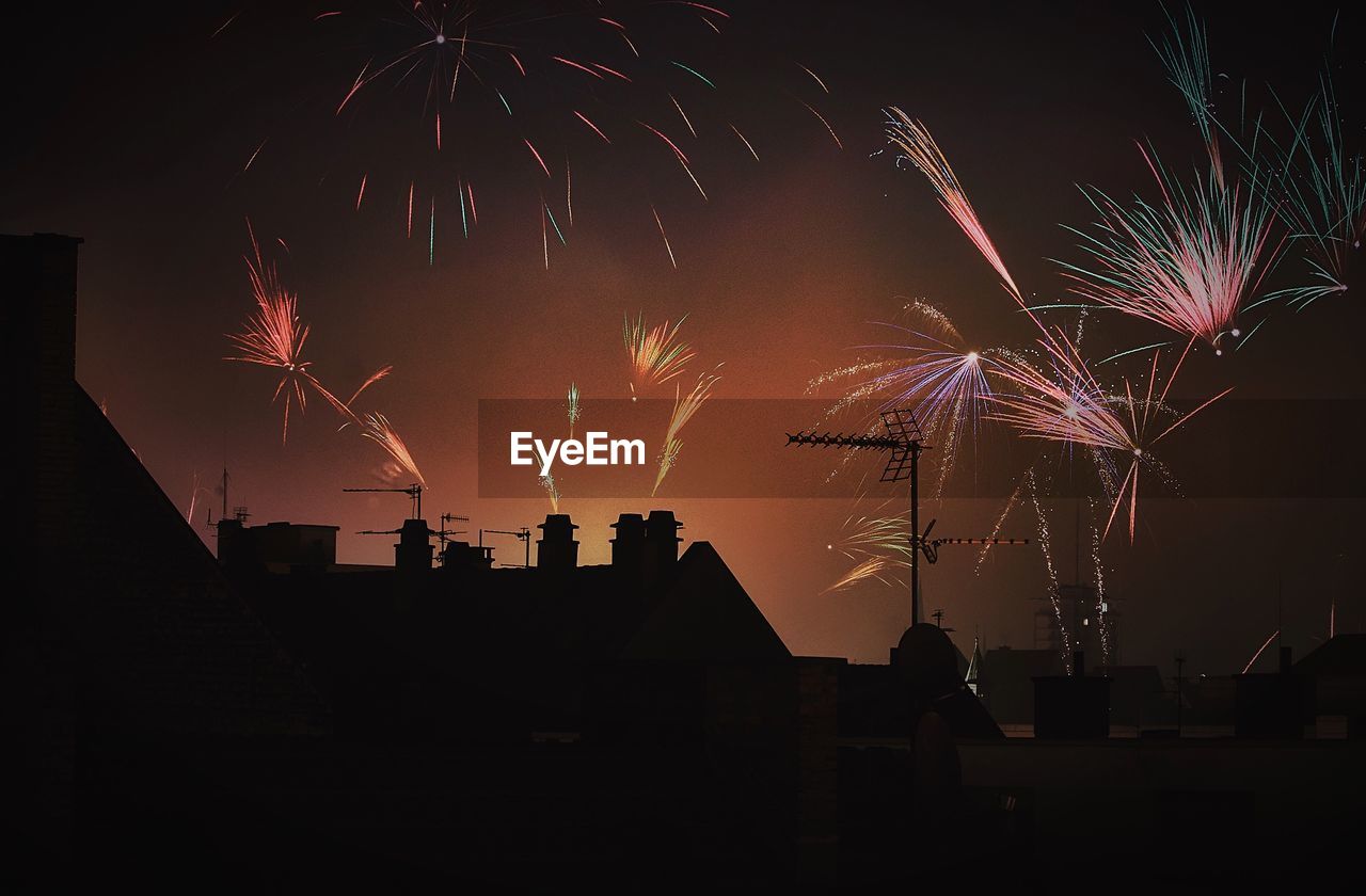 Low angle view of silhouette building against firework display