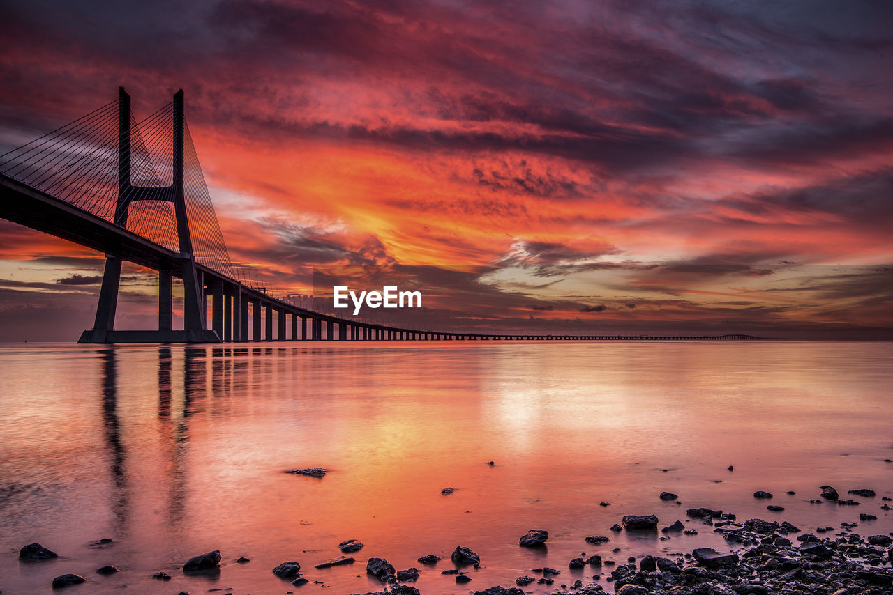 Scenic view of dramatic sky over bridge during sunset