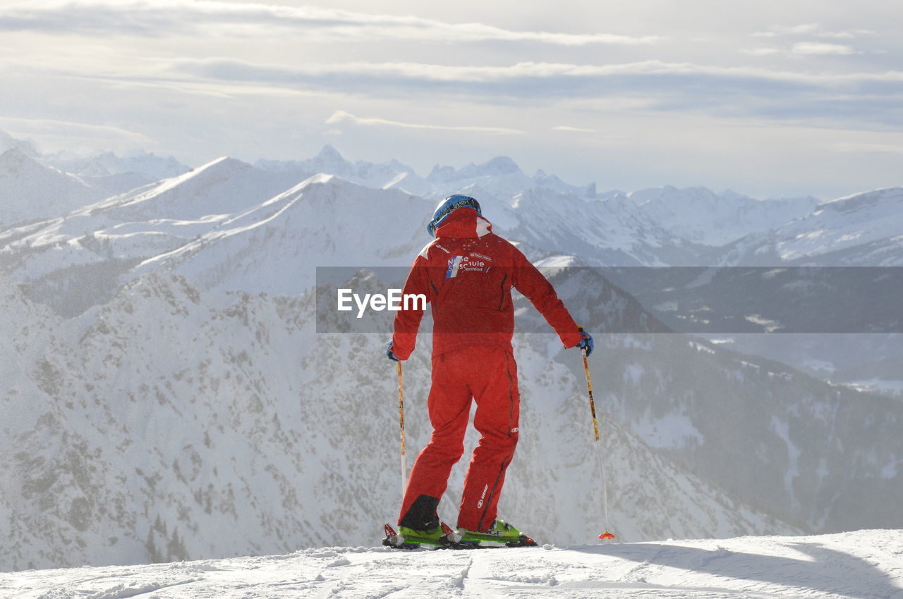 Rear view of man snowboarding on snowcapped mountain