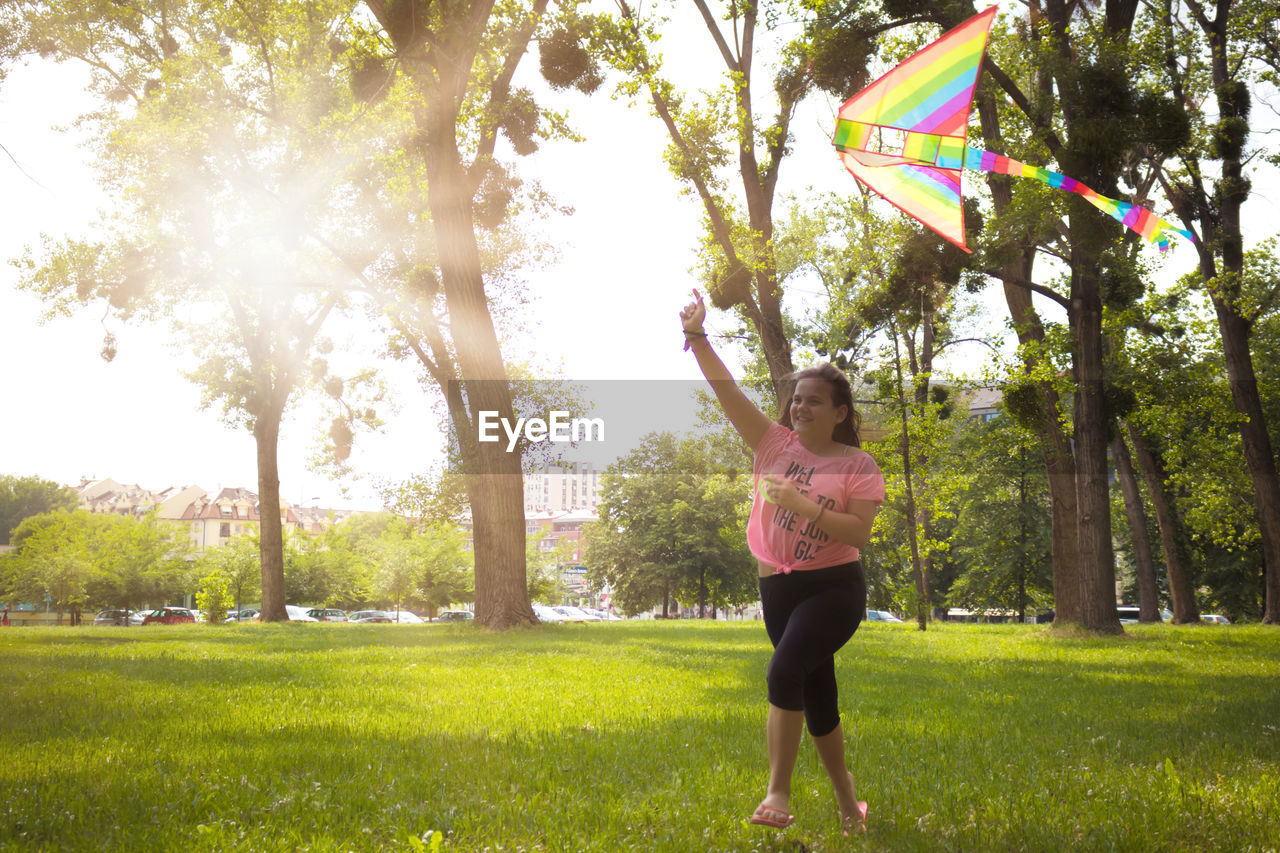 Carefree teenage girl running with a kite and having fun in the park.