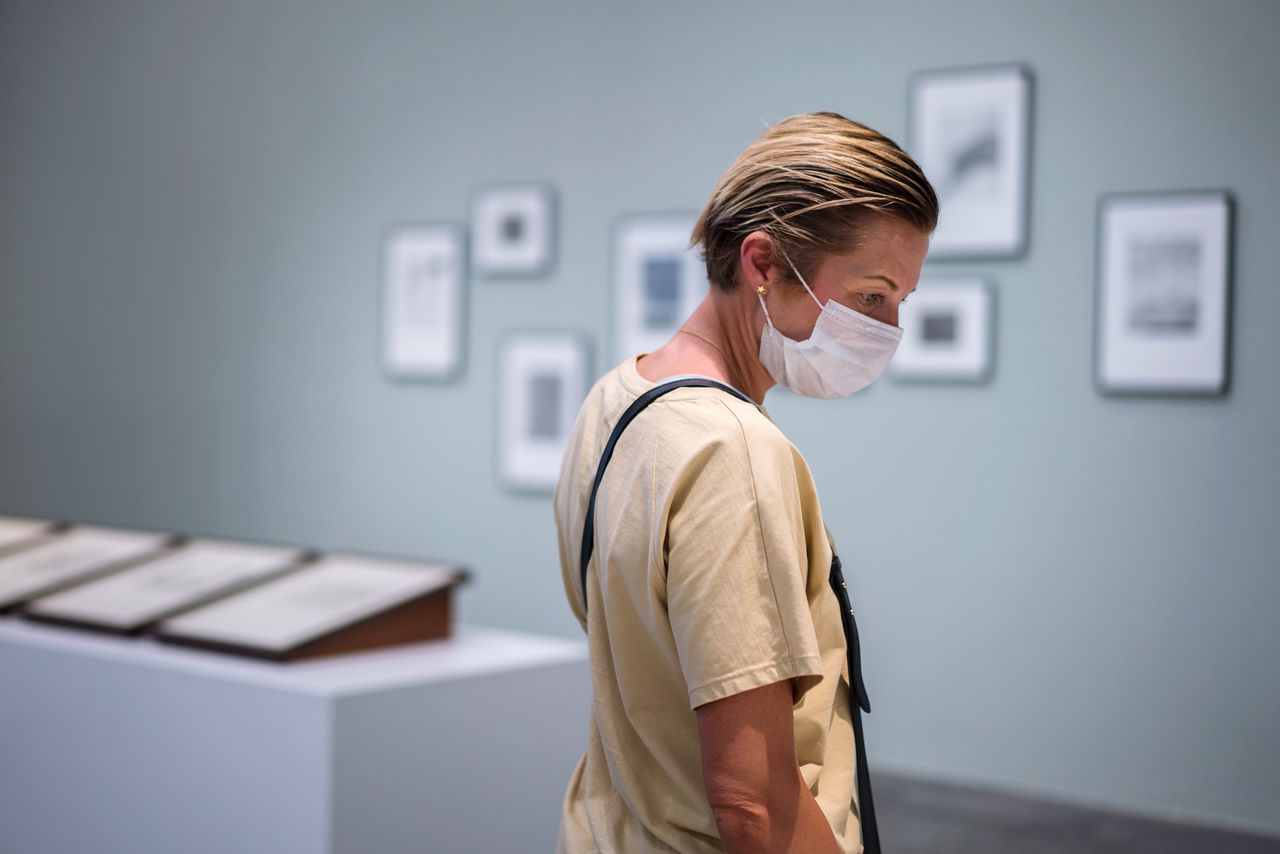 Woman looking at the painting in the art gallery wearing face mask