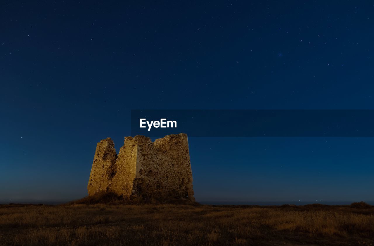 Low angle view of castle on field against sky at night