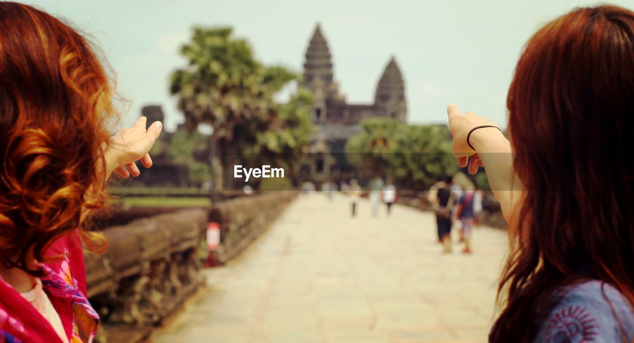 Rear view of woman pointing fingers towards temple