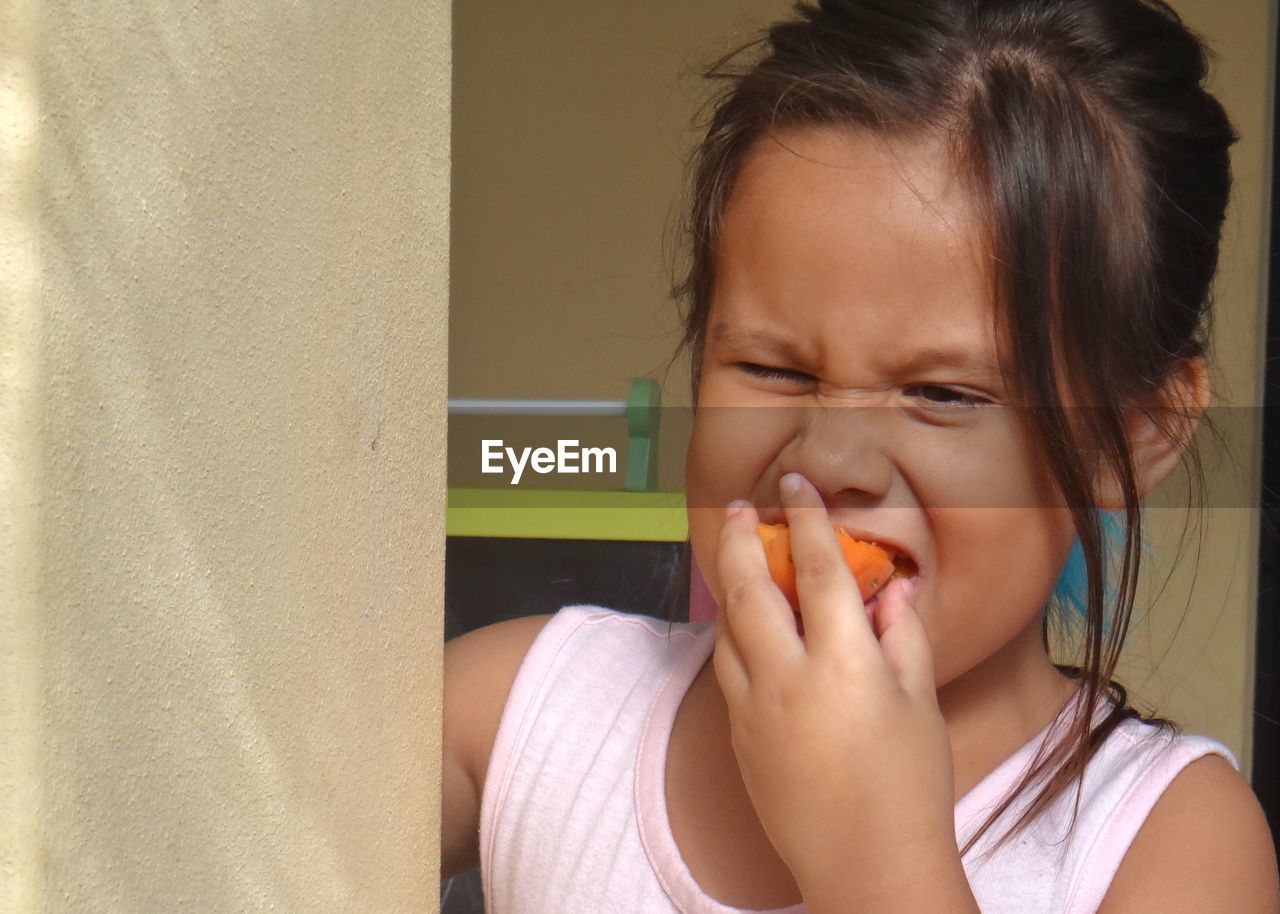 Cute girl eating apricot at home