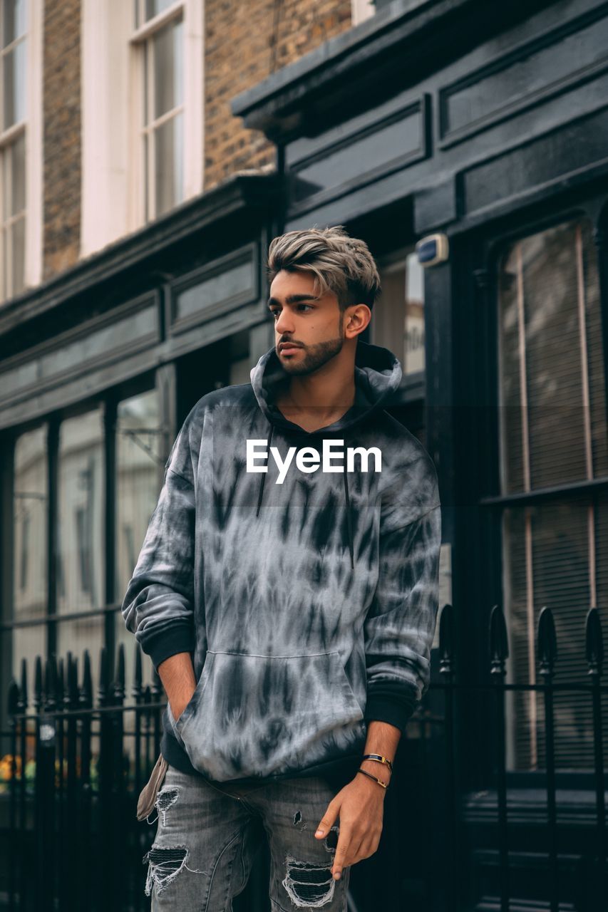 portrait of young man looking away while standing in city