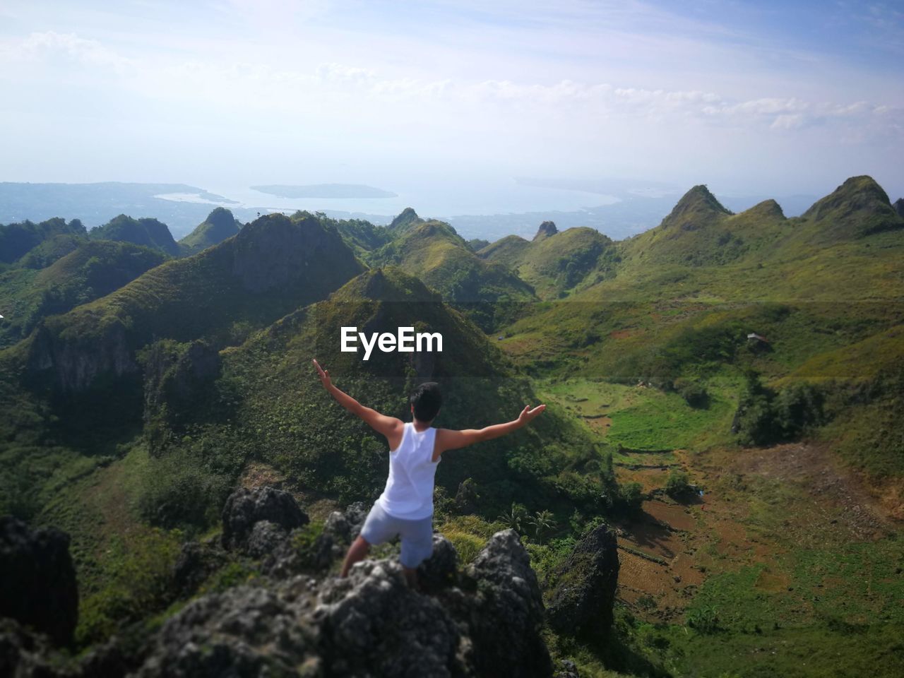 Rear view of man with arms outstretched standing on rock