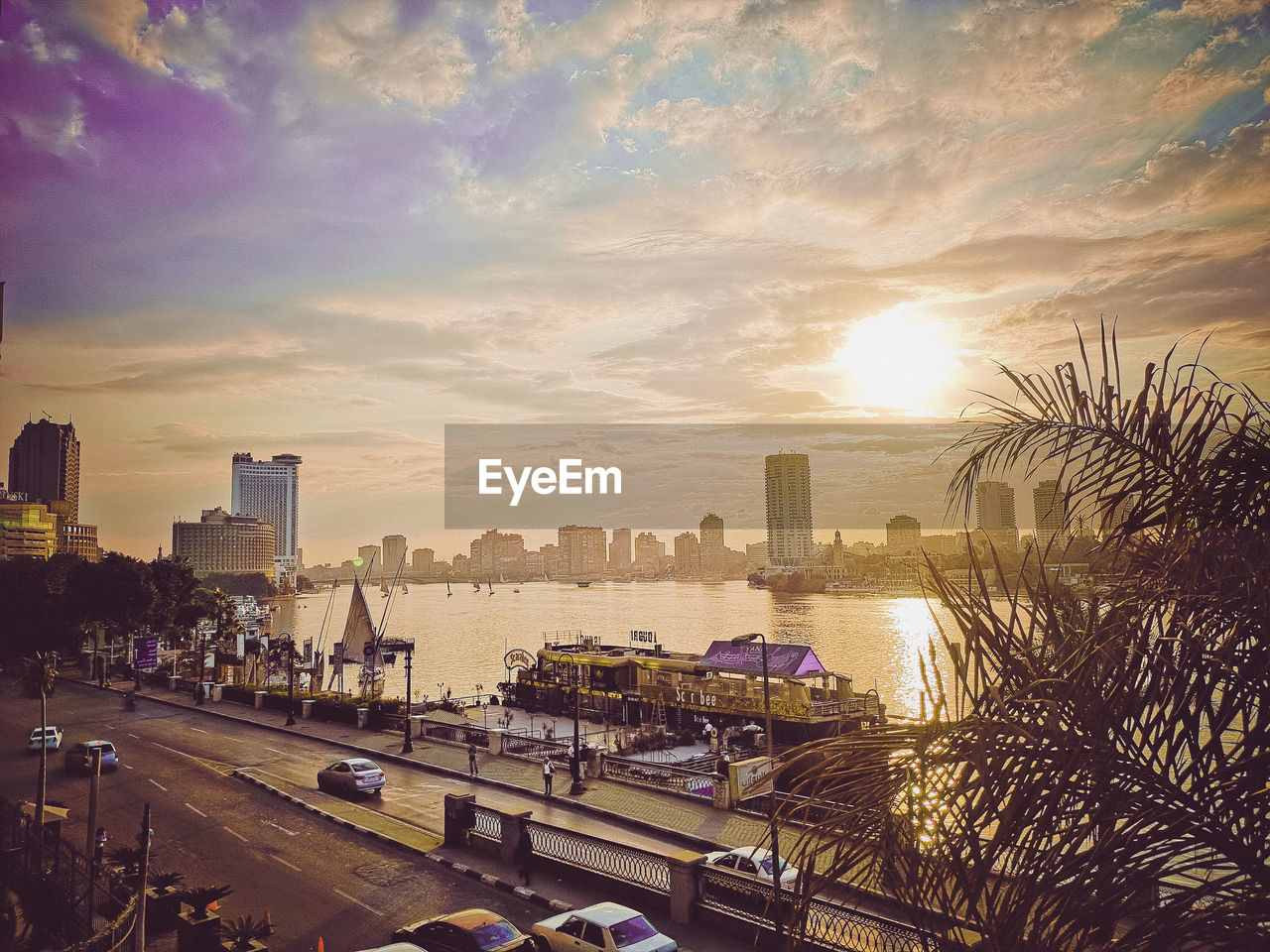 architecture, city, sky, built structure, building exterior, cityscape, evening, sunset, dusk, transportation, skyline, nature, building, horizon, urban skyline, mode of transportation, skyscraper, office building exterior, cloud, landscape, car, city life, travel destinations, motor vehicle, street, urban area, water, sunlight, road, travel, outdoors, high angle view, no people, traffic, reflection, land vehicle, tree, residential district, city street