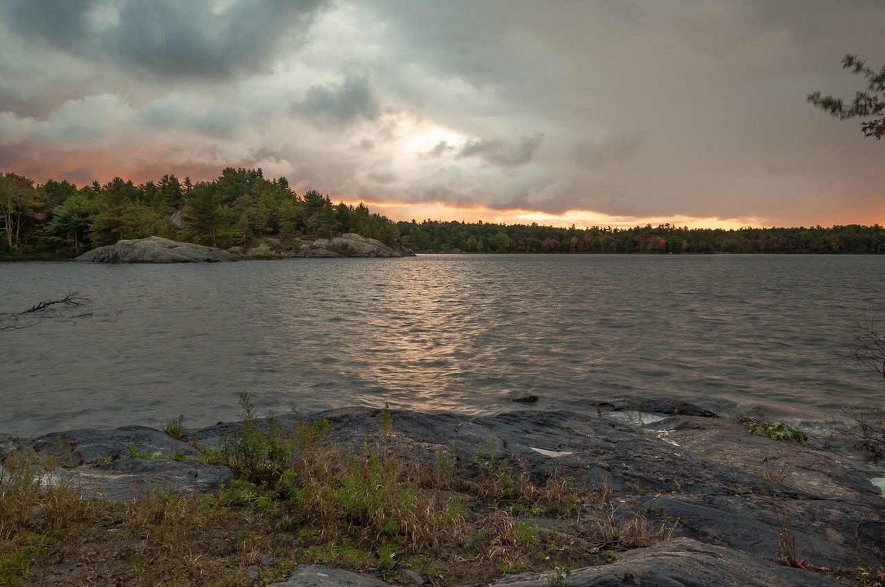 SCENIC VIEW OF CALM LAKE AGAINST CLOUDY SKY